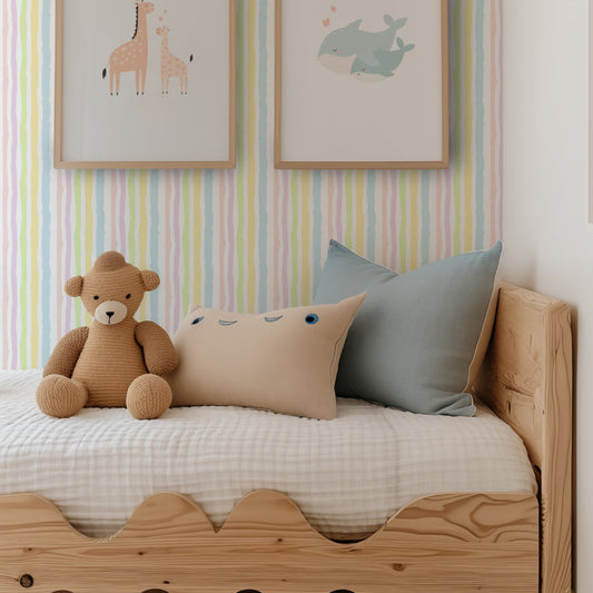 A styled children's bedroom corner featuring a light natural wood bed with a scalloped footboard, dressed in white bedding. A brown teddy bear sits on the bed next to a beige pillow and a dusty blue pillow.