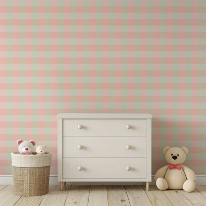 Blush and mint check wallpaper behind a white chest of drawers and a teddy bear