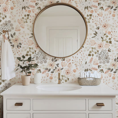Primavera blush floral wallpaper behind a white bathroom vanity with a round brass mirror