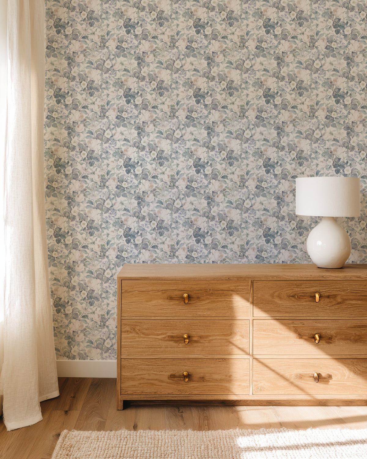 Vintage Veil rose wallpaper in a bedroom with an oak chest of drawers and table lamp